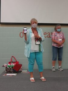 Two women on stage, one holding phone.