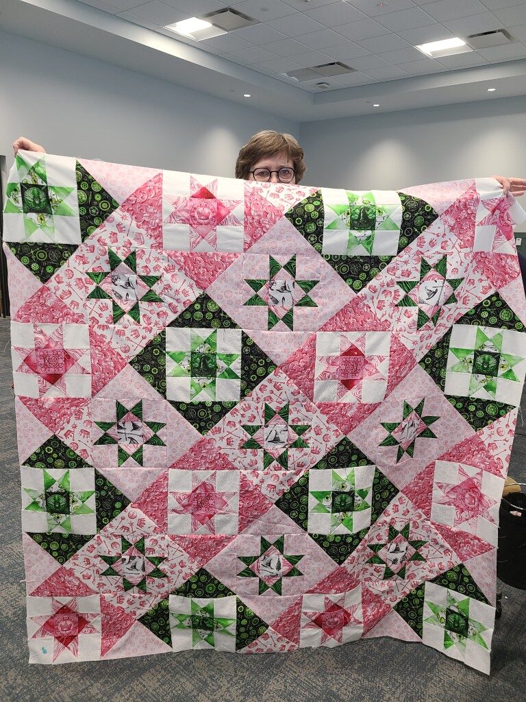Person holding colorful patterned quilt indoors.
